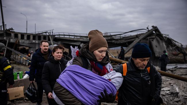 A woman carrying her baby crosses a destroyed bridge as they flee the city of Irpin, northwest of Kyiv. Picture: AFP