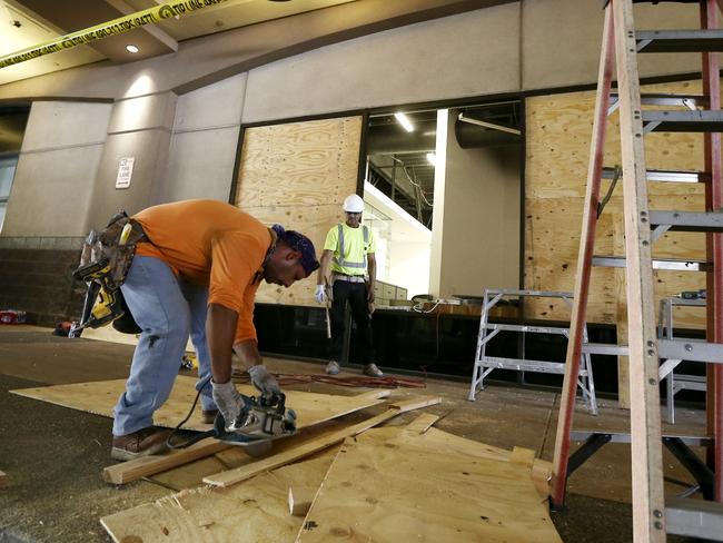 Contractors cut plywood as they board up broken window damaged at Scottsdale Fashion Square Mall.