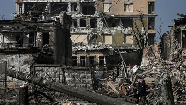 A couple walk in front of houses destroyed by shelling in Kharkiv, which Russia has claimed was a successful “first phase” Picture: AFP.