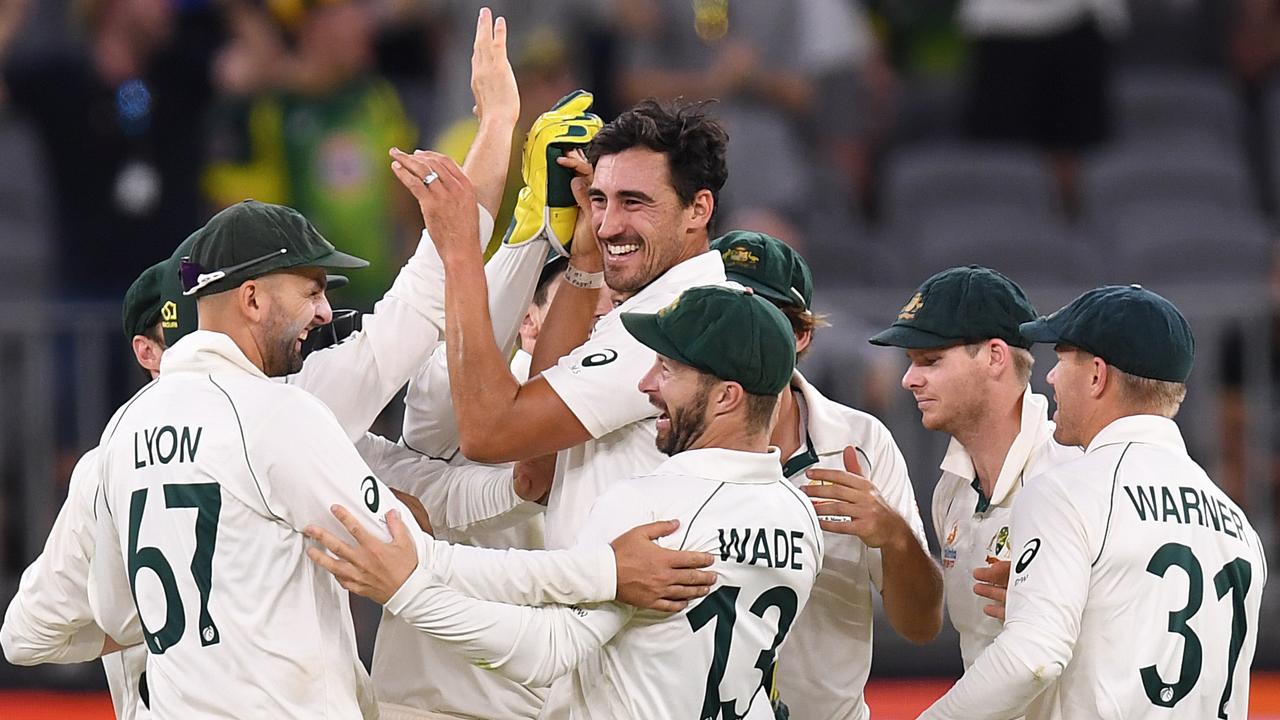 Mitchell Starc is mobbed by teammates after snaring a wicket late on day two in Perth.