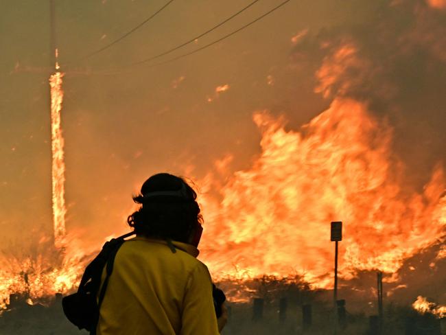 A member of the media watches flames from the Hughes fire fills race up the hill in Castaic, a northwestern area of Los Angeles. Picture: AFP