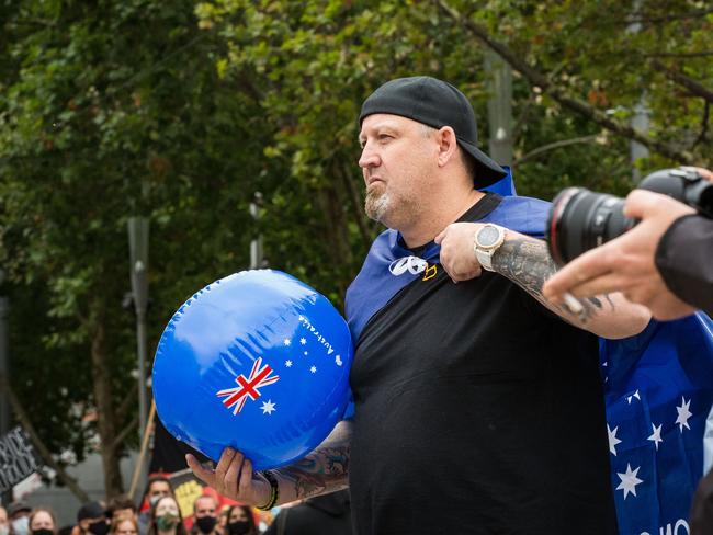 A man wearing a 'Proud Boys' shirt and an Australian flag attends the Invasion Day rally in Melbourne. Picture: Getty Images