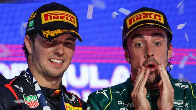 Red Bull Racing's Mexican driver Sergio Perez (L) celebrates on the podium next to Aston Martin's Spanish driver Fernando Alonso after winning the Saudi Arabia Formula One Grand Prix at the Jeddah Corniche Circuit in Jeddah on March 19, 2023. (Photo by Giuseppe CACACE / AFP)