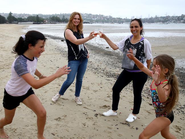 Locals Tammy Stone (back left) and Emma Grojnowski say cheers on Rose Bay beach that was closed off to the public, with only residents allowed access. Picture: Toby Zerna