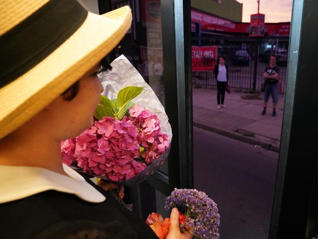 People wait at tram stops add their flowers to the 86 tram. Picture: AAP/Stefan Postles