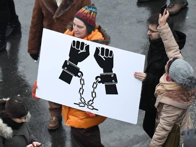 A protester holds a placard bearing handcuffed hands during a demonstration against the government's new labour reform, dubbed the "slave law" by the opposition on January 5, 2019 in Budapest. - The law, that was voted by Hungarian Parliament on December 12, 2018 and then signed by the President, hikes the amount of overtime that employers can demand from 250 to 400 hours per year and allows payment to be delayed by up to three years. (Photo by ATTILA KISBENEDEK / AFP)