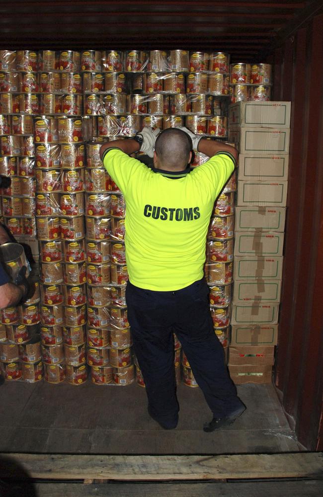 A customs agent unpacks canned tomato tins holding tonnes of ecstasy tablets. Picture: Australian Customs Service.