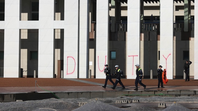 Police intercepted Extinction Rebellion protesters who were defacing Parliament House with red spray point but not before they wrote the words 'DUTY OF' on the front of the building. Picture: NCA/Gary Ramage