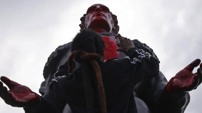 A protester spray paints the face of a statue of Christopher Columbus in Miami. Picture: Carl Juste/Miami Herald