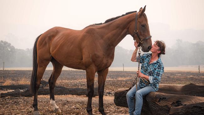 Robyn Sandy, 54, with her aptly named racehorse, Firefree, on their burnt out Buchan property. Picture: Jason Edwards