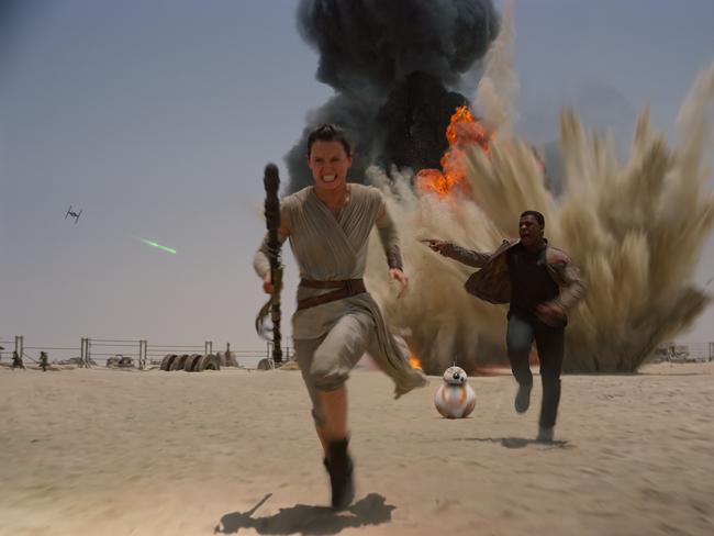 Daisy Ridley and John Boyega with droid BB-8 in a scene from film Star Wars: The Force Awakens.