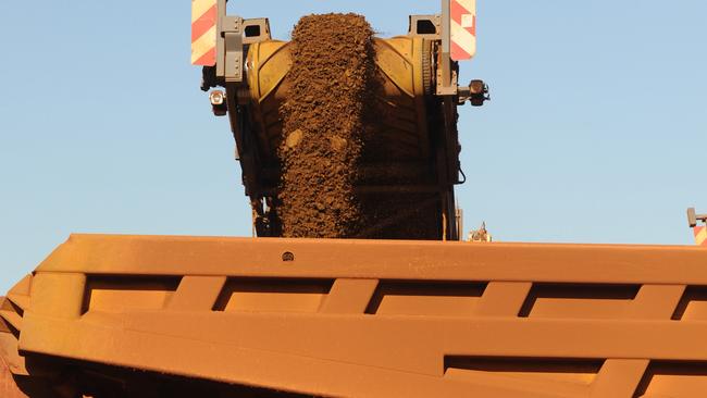 An earth mover receives iron ore from a surface miner in the mine pit at Fortescue Metals Group Ltd.'s Cloudbreak operation in the Pilbara region of Western Australia, on Monday, July 25, 2011. Fortescue Metals Group, Australia's third-biggest producer of iron ore, will release their full-year earnings on August 19. Photographer: Carla Gottgens/Bloomberg