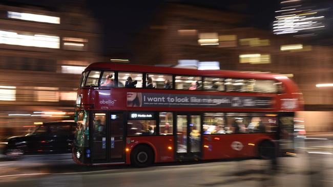 A red London bus and black taxi cab pass through central London. Picture: AFP