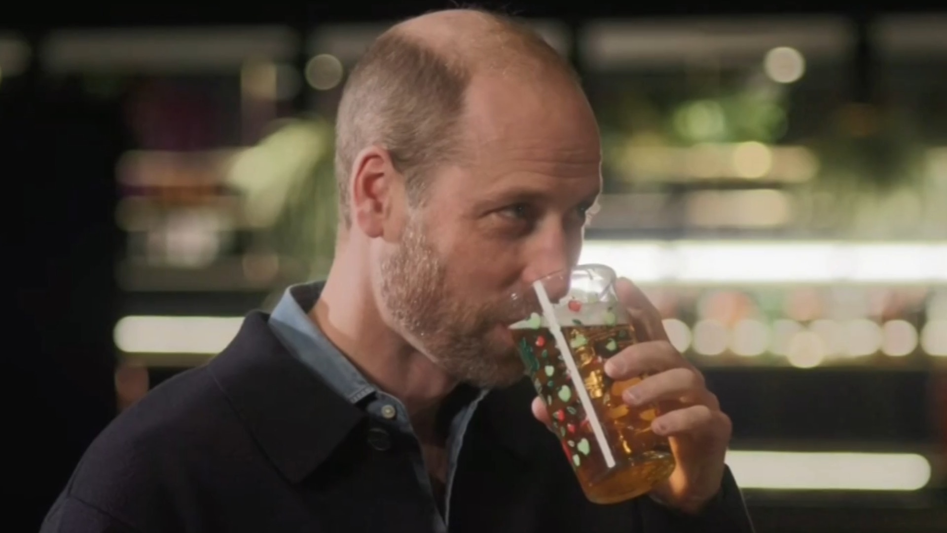 Prince William faces off in a game of darts while sipping beer