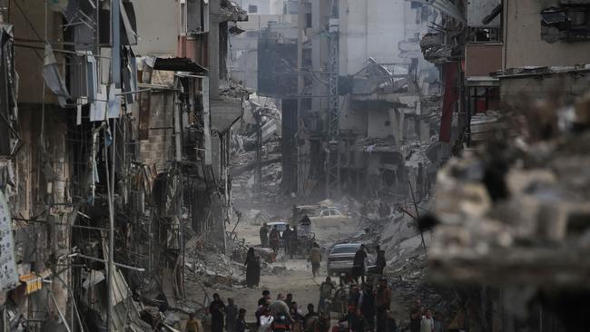 Palestinians walk past damaged buildings in Khan Younis after Israel pulled its ground forces out of the southern Gaza Strip. Picture: AFP.