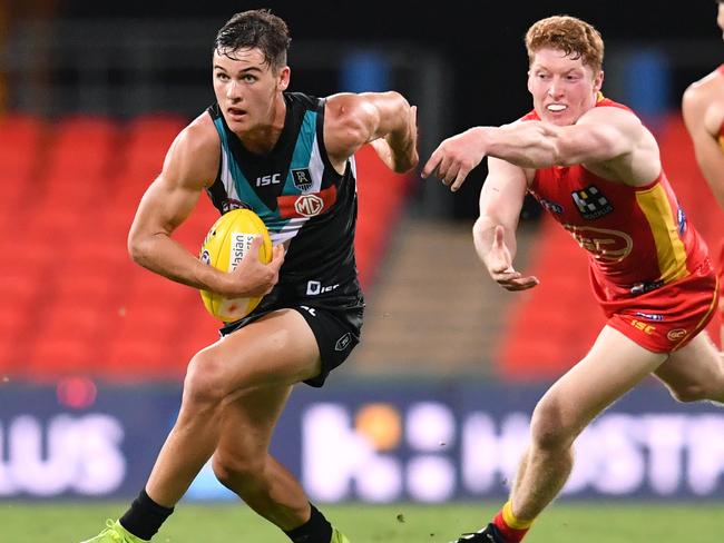 Connor Rozee (left) of the Power gets past Matthew Rowell (centre) of the Suns during the Round 1 AFL match between the Gold Coast Suns and Port Adelaide Power at Metricon Stadium on the Gold Coast, Saturday, March 21, 2020. (AAP Image/Darren England) NO ARCHIVING, EDITORIAL USE ONLY