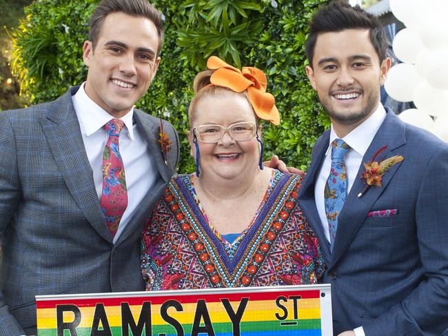 Matt Wilson’s Aaron Brennan and Takaya Honda’s David Tanaka with Magda Szubanski playing wedding celebrant Jemima Davies-Smythe in the same-sex marriage episode of Neighbours.