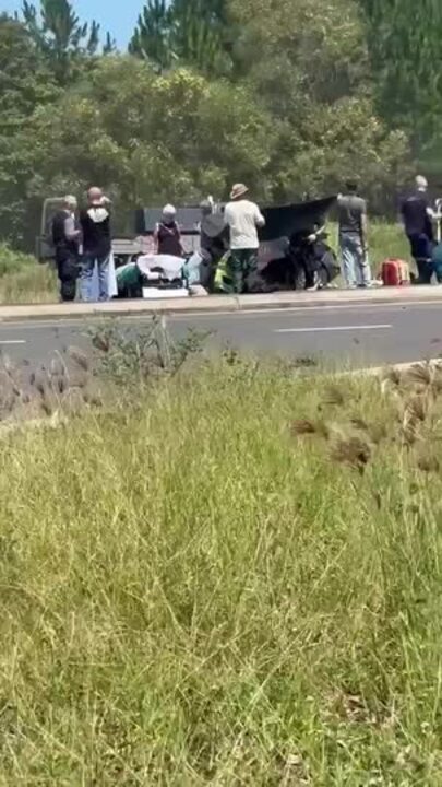 Paramedics and bystanders at the scene of a car vs motorcycle collision near Bauple, Bruce Highway.