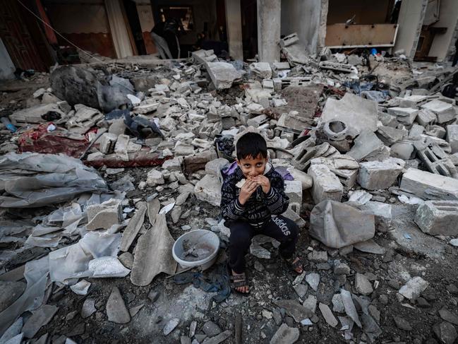 TOPSHOT - A child eats amid the rubble of destroyed buildings following Israeli bombardment in Rafah on the southern Gaza Strip on December 29, 2023, amid the ongoing battles between Israel and the Palestinian militant group hamas. (Photo by AFP)