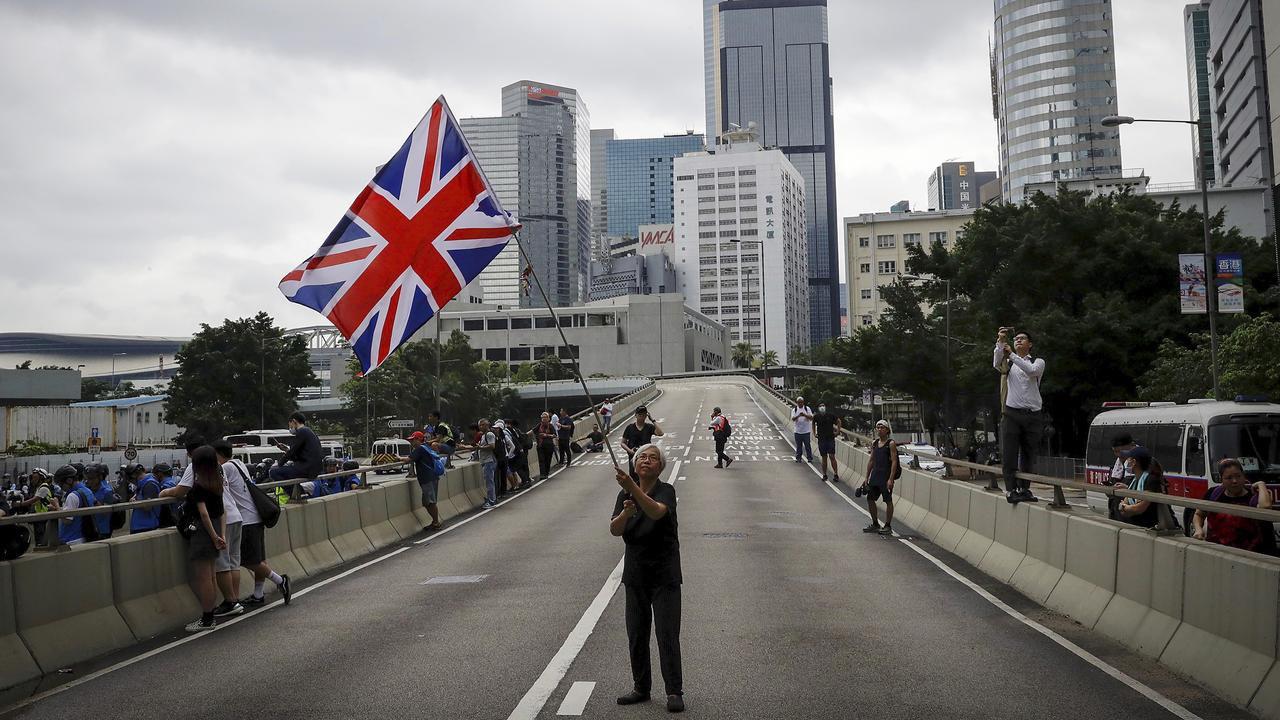 A man waves a British flag on a road as protesters gather outside the Legislative Council. Picture: Vincent Yu/AP