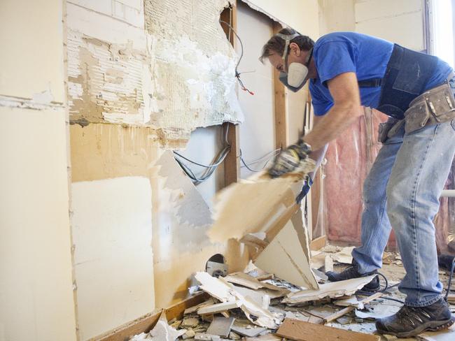 Man tearing out old kitchen during home renovations.