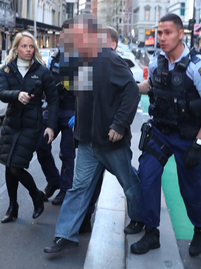 Police with a protester in King St on Monday morning. Picture: John Grainger