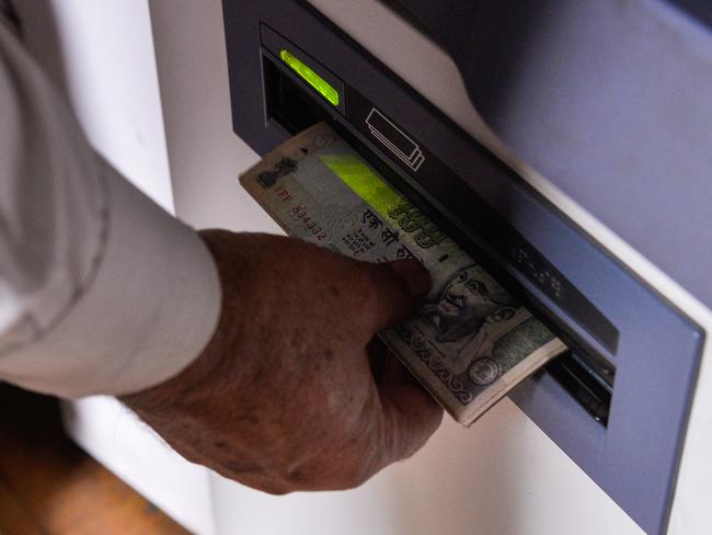 An Indian man withdraws money from a mobile bank ATM machine in New Delhi on November 15, 2016. India is to use indelible ink to prevent people from exchanging old notes more than once, the government said, a week after the withdrawal of high-value banknotes from circulation in a crackdown on "black money". / AFP PHOTO / CHANDAN KHANNA