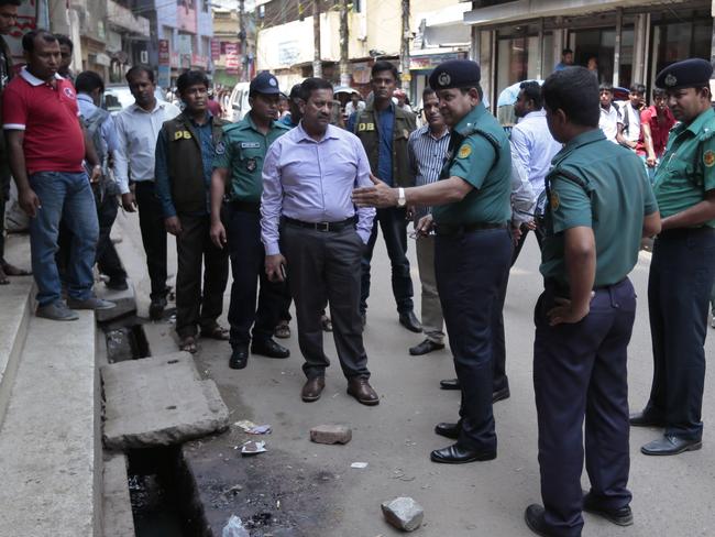 Bangladeshi police officers investigate at the spot where three motorcycle-riding assailants hacked student activist Nazimuddin Samad to death.