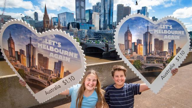 Annelise Cembala and Joe Wetzler with a large version of the new stamp Australia Post has created as part of the Let’s Melbourne Again campaign. Picture: Jay Town.