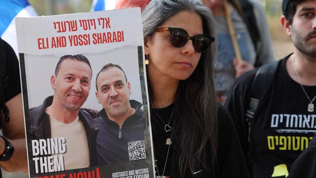 A woman holds a portrait of hostages Eli and Yossi Sharabi. Picture: AFP