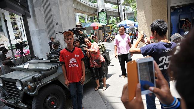 People pose for photos with Thai Army soldiers deployed on a downtown Bangkok street. Picture: Getty