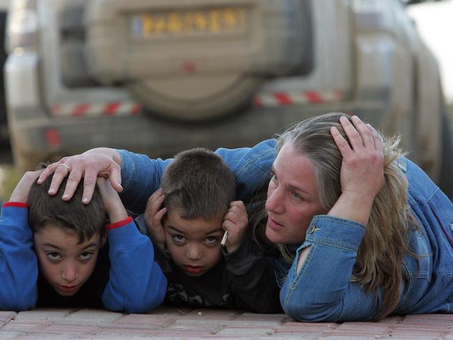 An Israeli mother protects her children as they take cover during a rocket attack alert in the southern Israeli Kibbutz of Kfar Aza, neighboring the Hamas-run Gaza Strip.