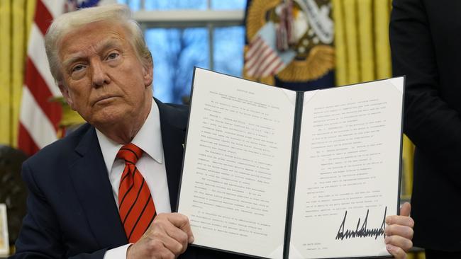 Donald Trump holds up an executive order in the Oval Office at the White House.