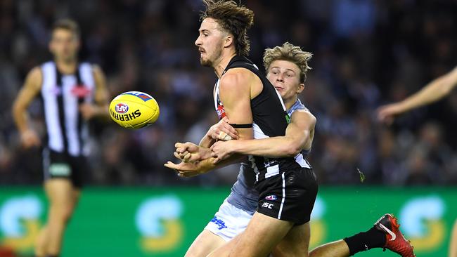 Tom Phillips of the Magpies handballs while being tackled by Xavier Duursma of the Power. Picture: Quinn Rooney/Getty Images