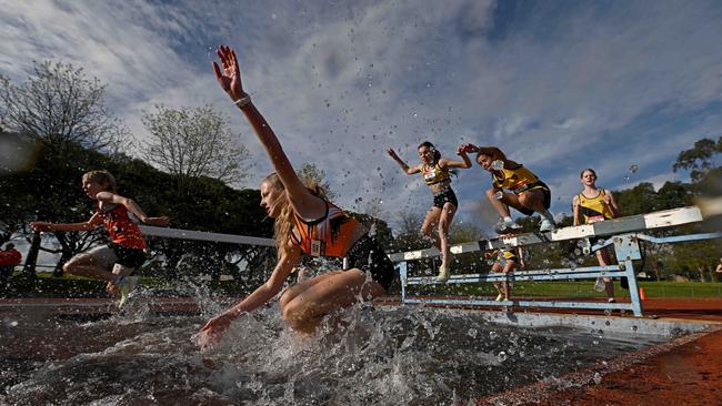 Charlee Dornom, Tilly Williams and Sarah Hastings attempt the water jump during the 2000m steeplechase. Picture: Andy Brownbill