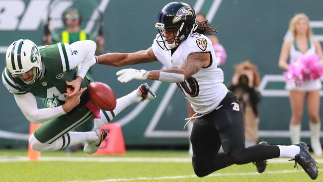 Lac Edwards #4 of the New York Jets fumbles the ball against Chris Moore #10 of the Baltimore Ravens in the first quarter.