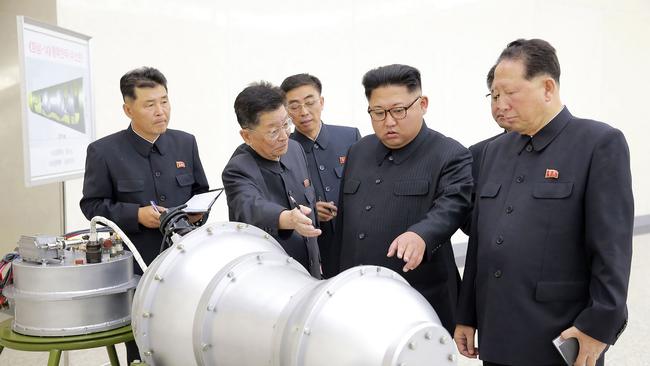 This undated picture released by North Korea's official Korean Central News Agency (KCNA) on September 3, 2017 shows North Korean leader Kim Jong-un (C) looking at a metal casing with two bulges at an undisclosed location. Picture: AFP