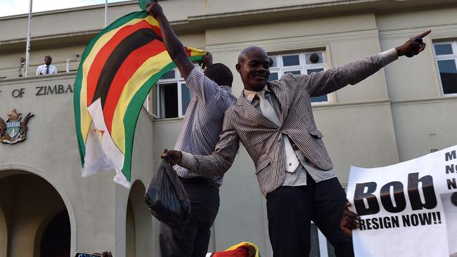 People wave national flags as they celebrate outside the parliament in Harare, after the resignation of Zimbabwe's president Robert Mugabe. Picture: AFP.