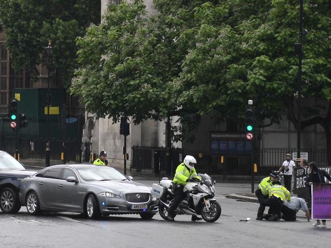 A protester is stopped and detained by police officers as he ran towards the car of Britain's Prime Minister Boris Johnson. Picture: AFP