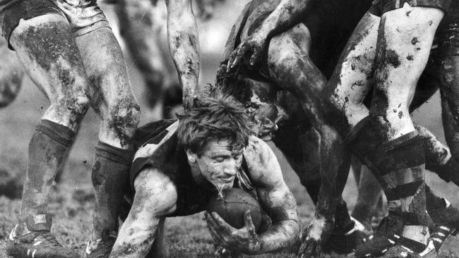 SANFL Football – Glenelg vs Norwood match at Glenelg Oval, 16 Aug 1986. Glenelg's Chris McDermott ploughs through a sea of mud and a forest of legs. The photograph won "The Advertiser" staff photographer Stuart Hannagan first prize in the International Sports Photo Concours.