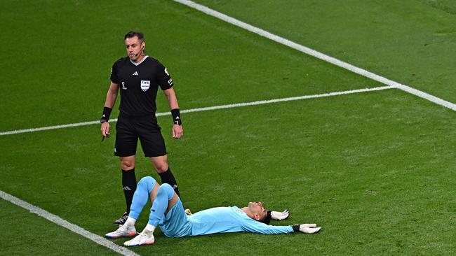 Alireza Beiranvand lies on the pitch next to Brazilian referee Raphael Claus