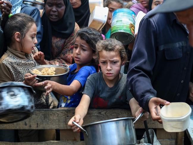 Palestinians gather to receive a hot meal at a food distribution point in the Nuseirat camp for refugees in the central Gaza Strip on May 21, 2025. Gazans waited desperately for vital supplies on May 21 after Israel said it let in dozens of UN trucks but faced mounting international pressure to increase the aid flow and abandon its intensified military campaign. (Photo by Eyad BABA / AFP)