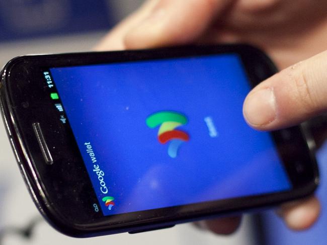 FILE - In this Jan. 17, 2012 file photo, a person tries a smartphone loaded with Google Wallet at the National Retail Federation in New York. Google is teaming up with three major U.S. wireless carriers in an effort to prod more people into using its mobile wallet and undercut the rapid success of Apple's rival payment service. (AP Photo/Mark Lennihan, File)