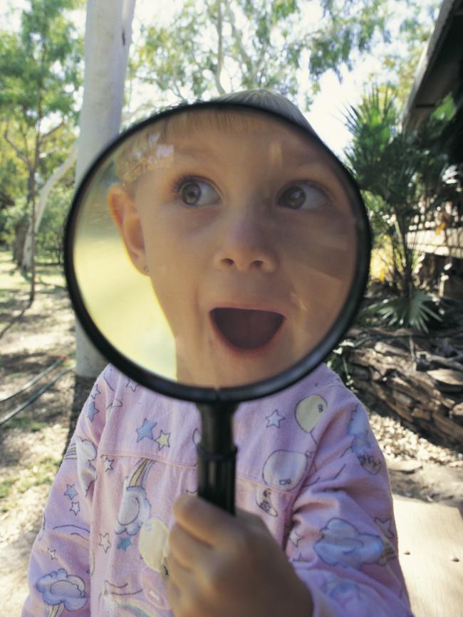 A Portrait of Australia: The best stories from 30 years of Australian Geographic. Four year old Bindi-Lee looks through a magnifying glass Photo by Bill Bachman