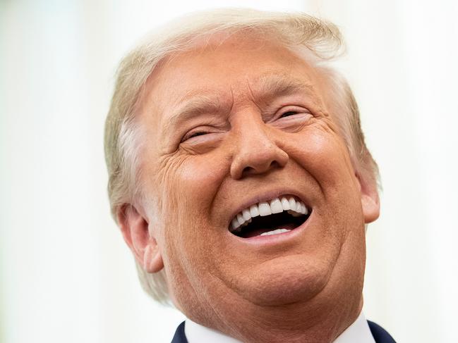 FILE:  US President Donald Trump laughs during a Medal of Freedom ceremony for Lou Holtz in the Oval Office of the White House on December 3, 2020, in Washington, DC. (Photo by Brendan Smialowski / AFP)