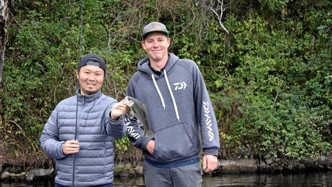 SMALL BEGINNINGS: Zaiyu Hasegawa, with bass fishing champion Braden Schuch, started small with this Australian bass, which he quickly returned to the water. Picture: Arthur Gorrie