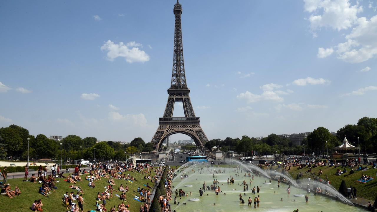 People cool off and sunbathe by the Trocadero Fountains next to Paris’s Eiffel Tower during a heatwave that broke records last month. Picture: Bertrand Guay/AFP