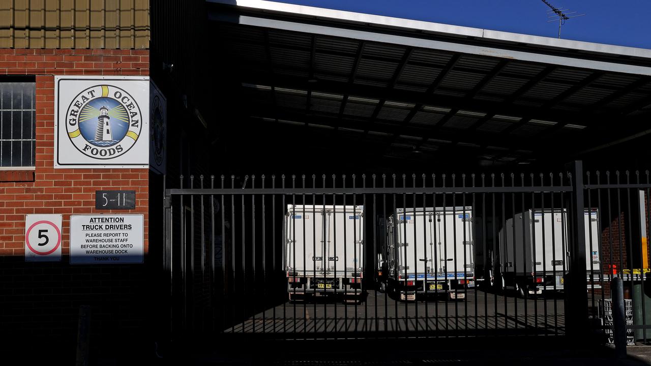 Trucks at Great Ocean Foods sit behind locked gates in Marrickville after two cases reported on Saturday were linked to the site. Picture: NCA NewsWire/Dylan Coker