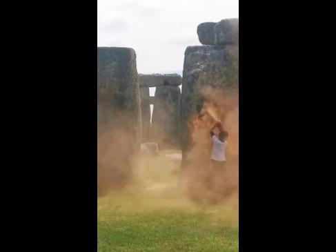 Onlookers try to drag away activists blasting paint on Stonehenge