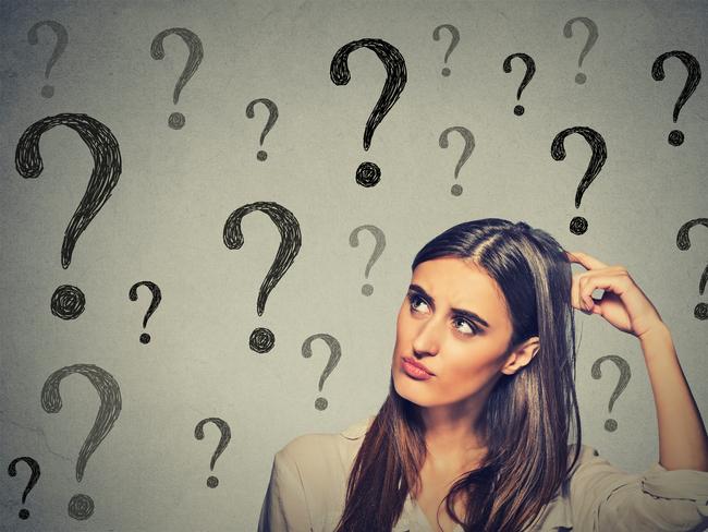 Portrait confused thinking young woman bewildered scratching her head seeks a solution looking up at many question marks isolated on gray wall background. Human face expression